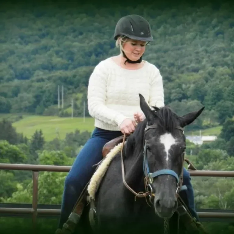 Nicole - sitting on a horse with a fence and hills in the background